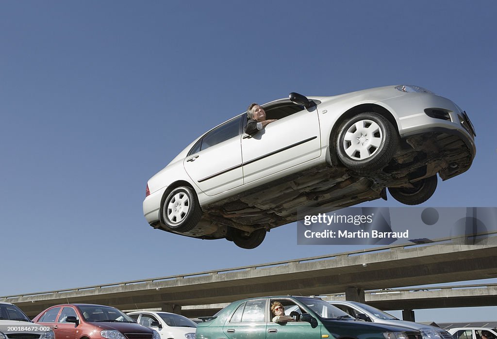 Mature man in car in air above people in traffic jam