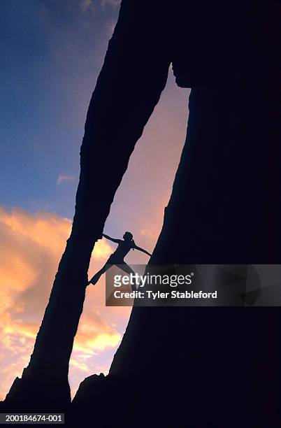 silhouette of female rock climber climbing rock formation at sunset - escalada libre fotografías e imágenes de stock