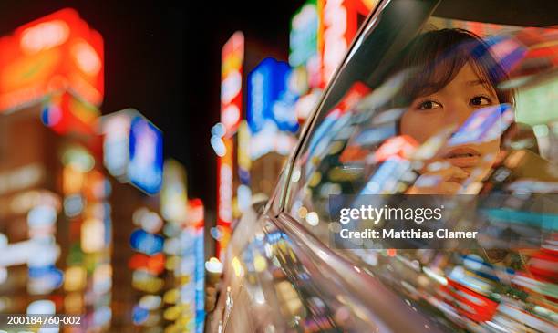 young woman looking out of car, building reflected in window, close-up - car reflection stock-fotos und bilder