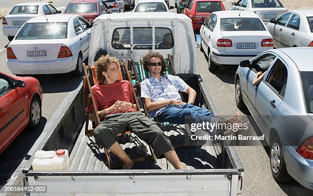 two men on deckchairs in back of pickup truck amongst traffic jam - roadblock stock-fotos und bilder