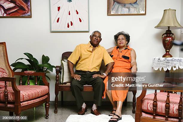 mature couple on chair in living room, portrait - yellow shirt stock pictures, royalty-free photos & images