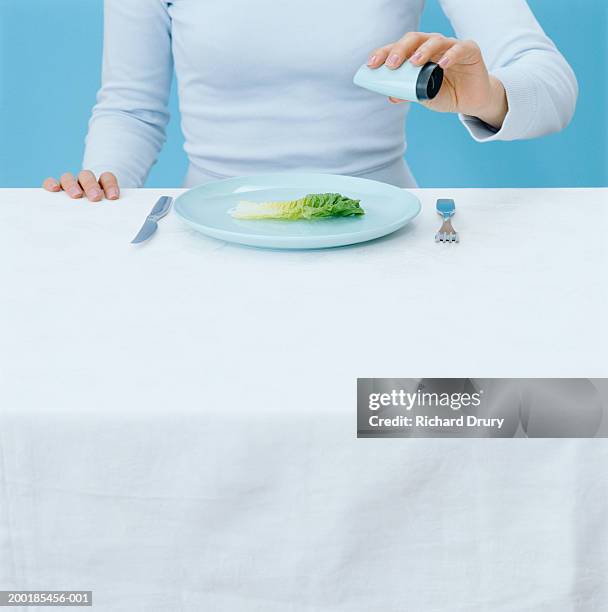 woman seasoning lettuce leaf, mid section - table cloth stockfoto's en -beelden