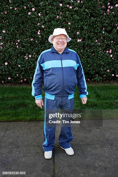 senior man wearing tracksuit, standing in front of hedge, portrait - chándal fotografías e imágenes de stock