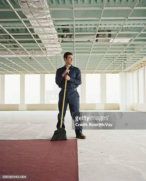 janitor holding broom in empty office space - hauswart stock-fotos und bilder