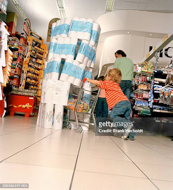 boy (2-4) pushing mini supermarket trolley into toilet roll display - ofog bildbanksfoton och bilder