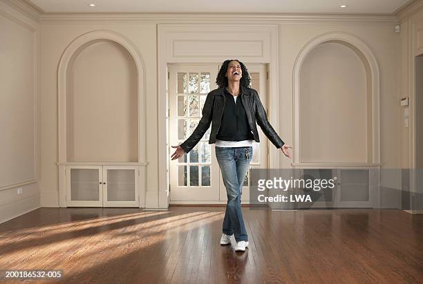 woman standing in barren room, arms outstretched, smiling - looking at camera foto e immagini stock