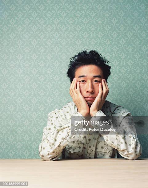 man sitting with head in hands, resting elbows on table, portrait - boredom man fotografías e imágenes de stock