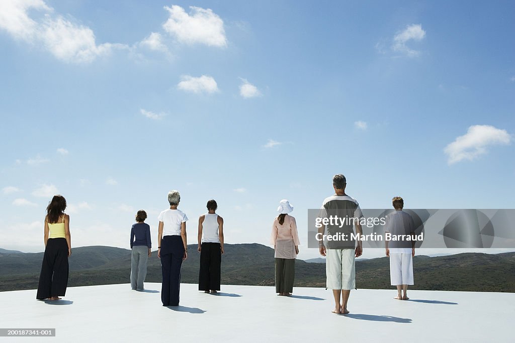 Group of people on platform in rugged landscape, rear view