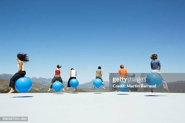 group of people bouncing on inflatable hoppers, on platform, outdoors - hoppity horse stock pictures, royalty-free photos & images