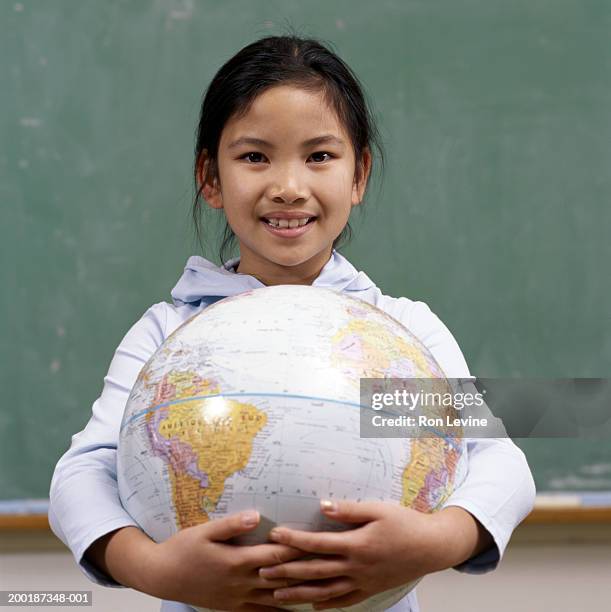 girl (8-10) holding world globe in classroom, portrait - equador latitude - fotografias e filmes do acervo