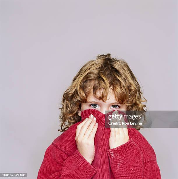 girl (5-7) pulling sweater collar over lower face, portrait - trouble maker studios stock pictures, royalty-free photos & images