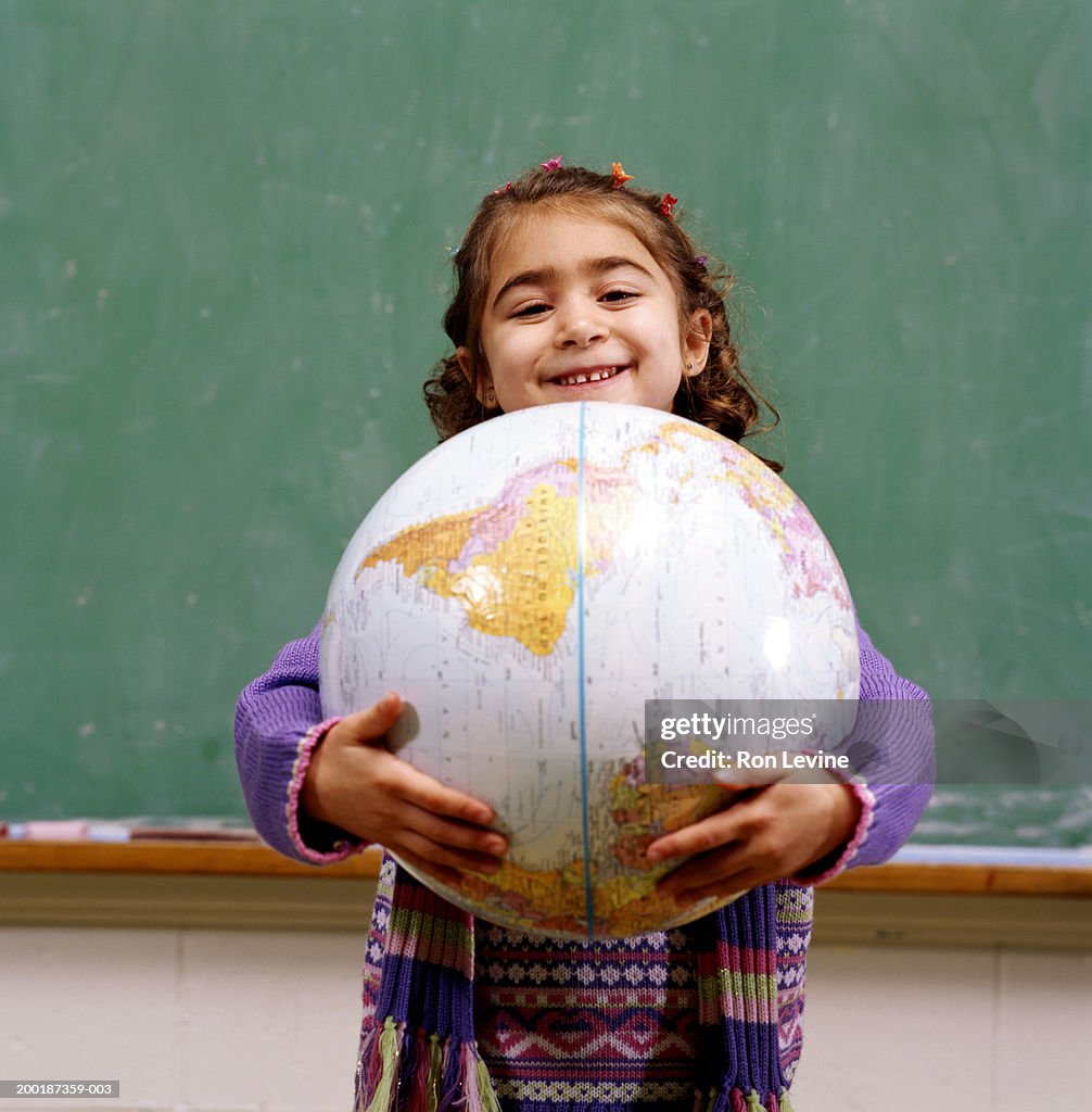 Girl (4-6) holding world globe, portrait