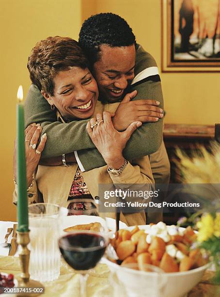 young man hugging grandmother at dinner table, smiling - thanksgiving dog stock pictures, royalty-free photos & images