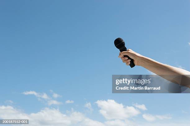 woman holding microphone, arm outstretched, outdoors, close-up - holding microphone stock pictures, royalty-free photos & images