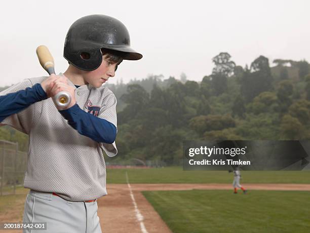 boy (11-13) standing on baseball field, bat over shoulder, side view - baseball helmet stockfoto's en -beelden