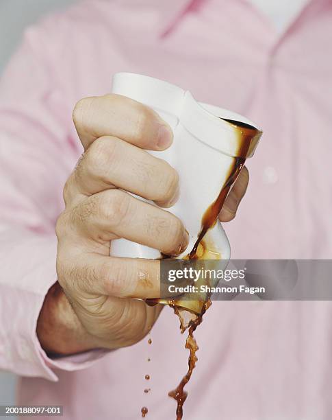 man crushing polystyrene cup filled with black coffee, close-up - zerdrückt stock-fotos und bilder