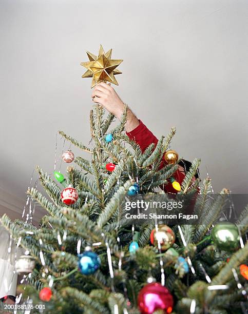 teenage boy (14-16) putting star on christmas tree - decorar fotografías e imágenes de stock