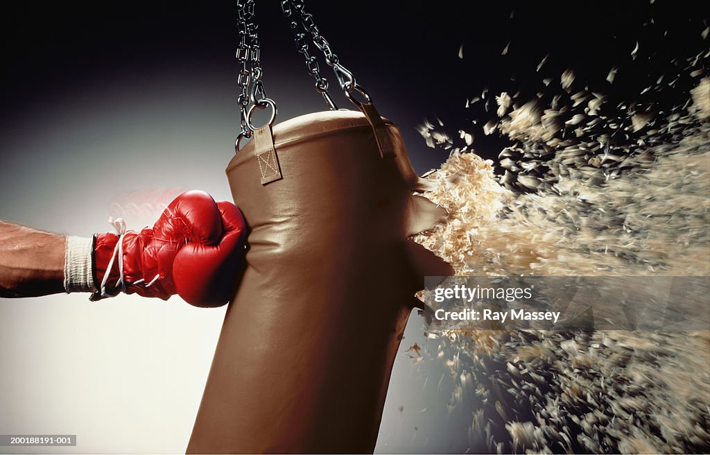 Man punching punch bag and stuffing exploding from bag