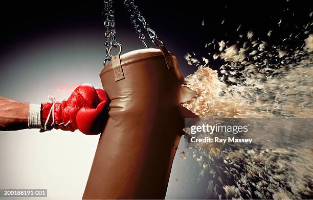 man punching punch bag and stuffing exploding from bag - faustschlag stock-fotos und bilder