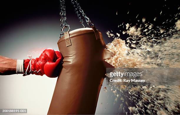 man punching punch bag and stuffing exploding from bag - punching stock pictures, royalty-free photos & images