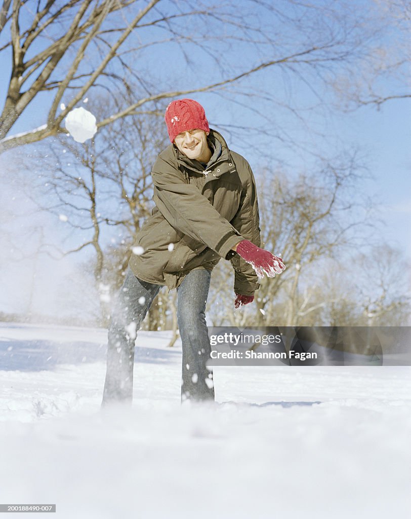 Man throwing snowball smiling, portrait