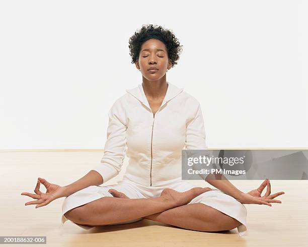 woman in yoga position meditating - schneidersitz stock-fotos und bilder