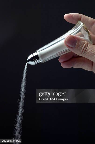 man pouring salt from salt shaker, close-up - salt shaker stockfoto's en -beelden