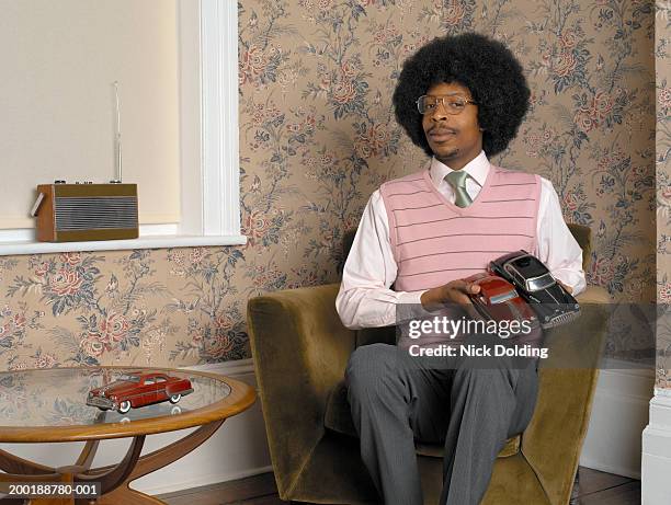 young man sitting in living room, holding model cars, portrait - 20th century model car stock pictures, royalty-free photos & images