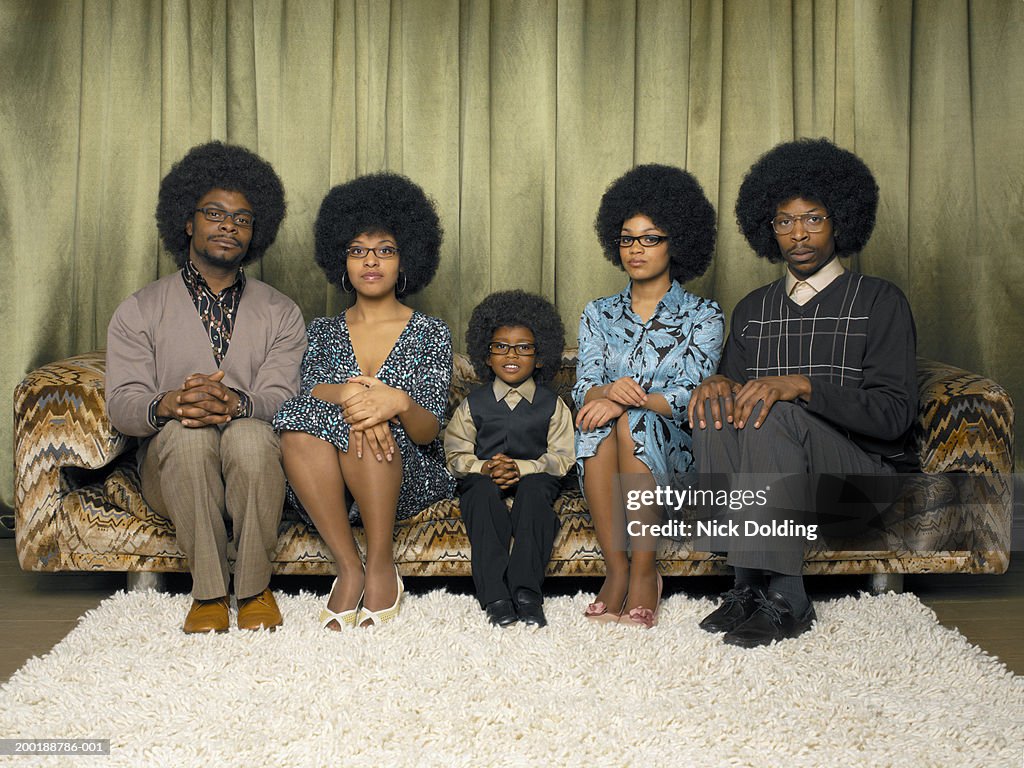 Family sitting on sofa, smiling, portrait