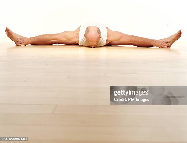 senior man with legs stretched outward, leaning forward, ground view - doing the splits stock pictures, royalty-free photos & images