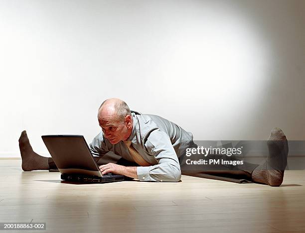 senior man with legs stretched outward using laptop, side view - doing the splits stock pictures, royalty-free photos & images