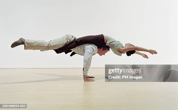 businessman doing handstand, balancing woman on back, side view - intertwined photos et images de collection