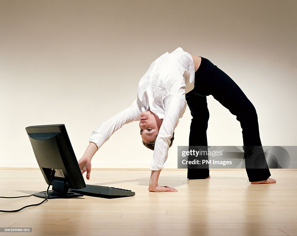 Businesswoman bent over backwards using laptop