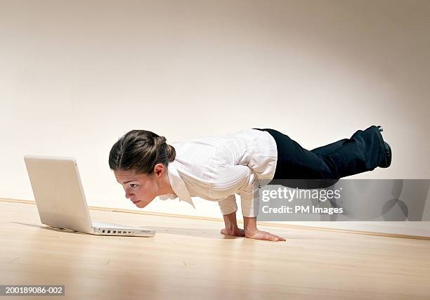 businesswoman performing horizontal handstand, looking at laptop - businesswoman handstand stock-fotos und bilder