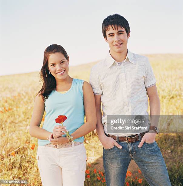 casal jovem em campo, mulher segurando papoula (eschscholtzia califo - manga curta - fotografias e filmes do acervo