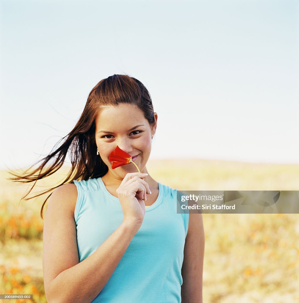 Junge Frau hält Mohn (Eschscholtzia californica)