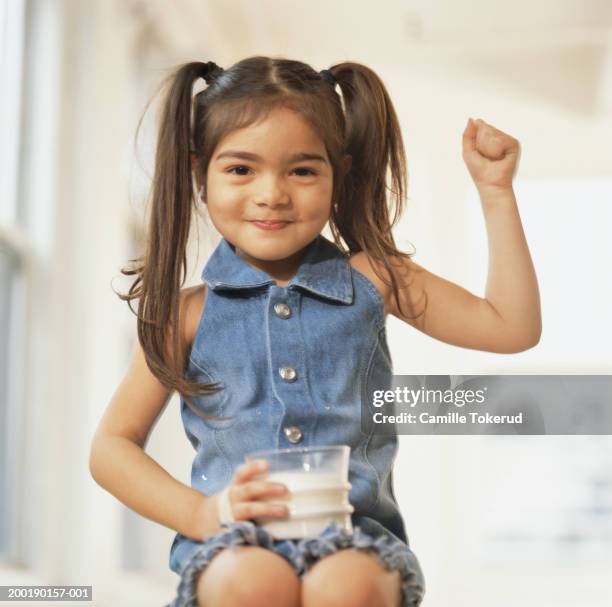 girl (3-6) with glass of milk on lap, smiling, portrait - codino foto e immagini stock