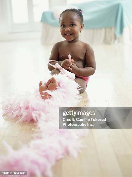 girl (1-3) on floor with feather boa, smiling, portrait - one baby girl only fotografías e imágenes de stock