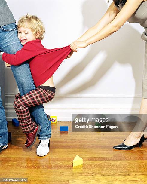 woman tugging girl (2-4) clinging to mother's leg, low section - pants pulled stock-fotos und bilder