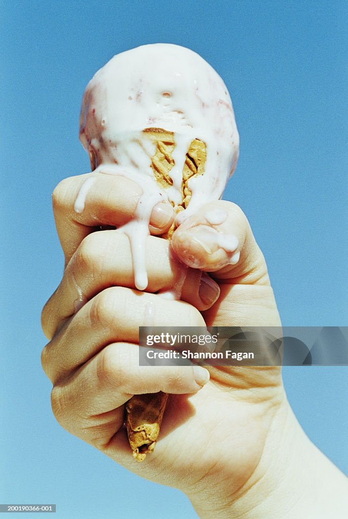 Woman holding melting ice cream cone, close-up