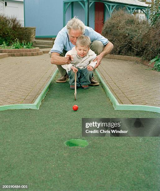 grandfather teaching grandson (3-5) to play crazy golf - mini golf stock pictures, royalty-free photos & images