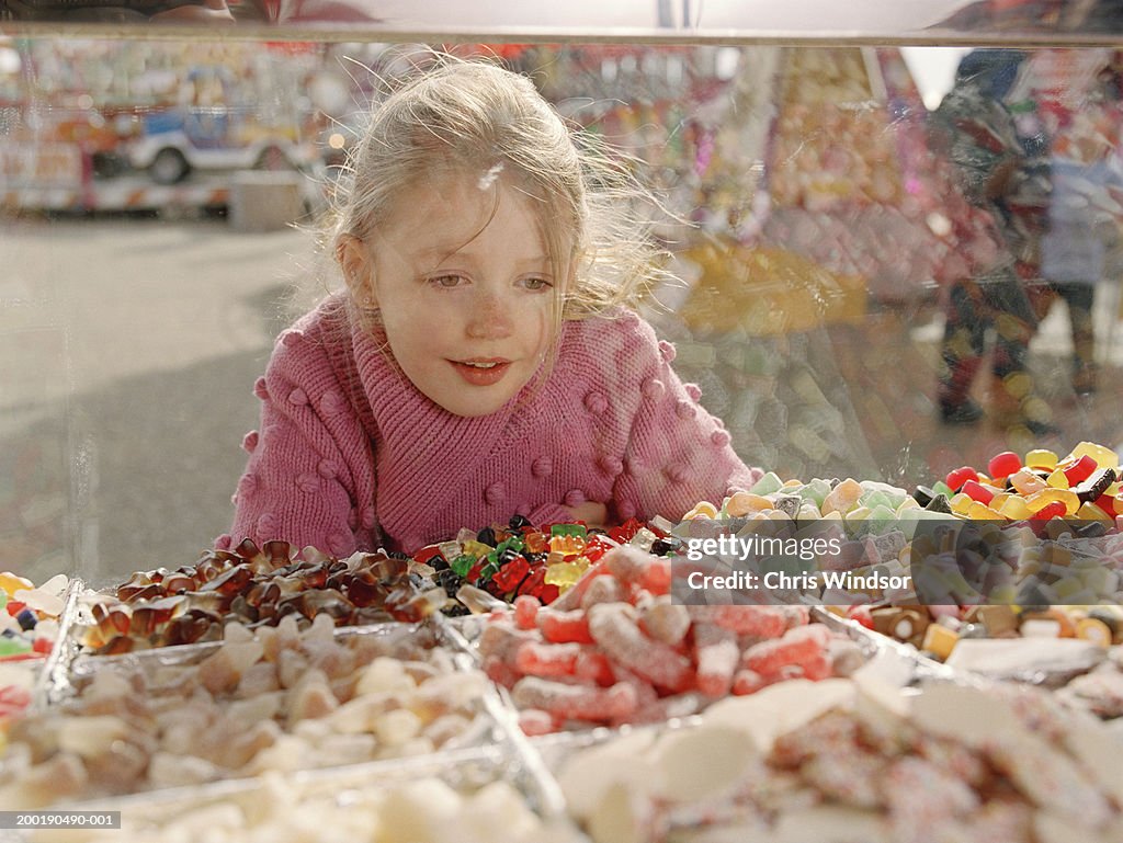 Girl (7-9) looking at sweets in glass counter