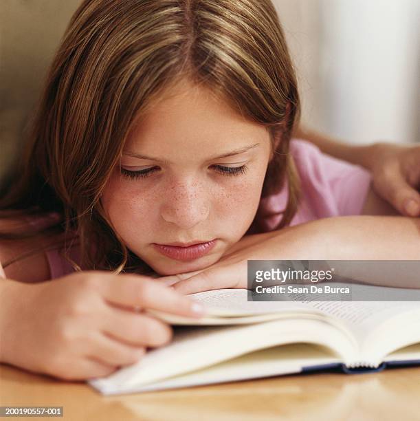 woman behind girl (9-11) reading book, close-up - sfogliare libro foto e immagini stock