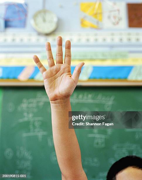 boy (8-10) raising hand in classroom, close-up - lever la main photos et images de collection