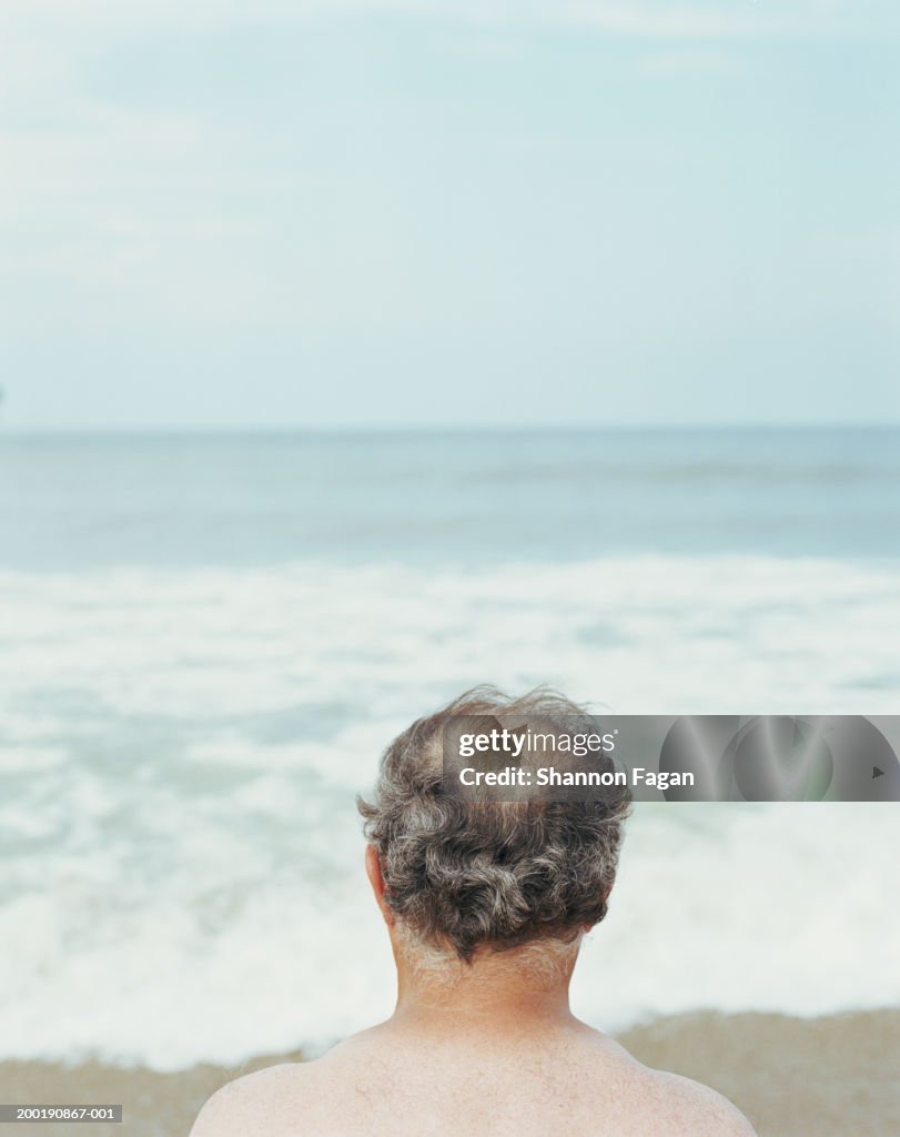 Senior man looking at ocean, rear view, close-up