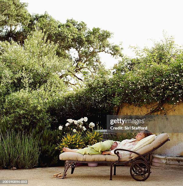 mature woman relaxing on lounge chair - achterover leunen stockfoto's en -beelden