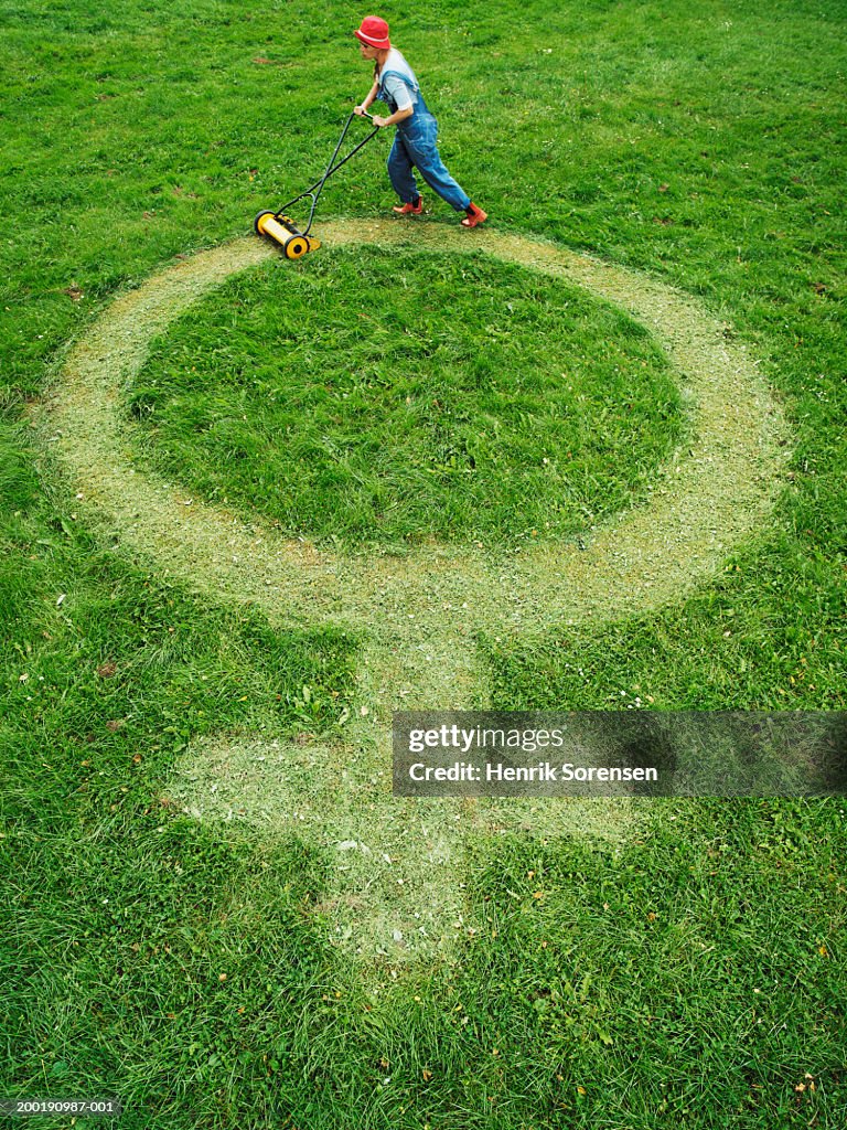 Woman mowing cross and circle female symbol on grass, elevated view