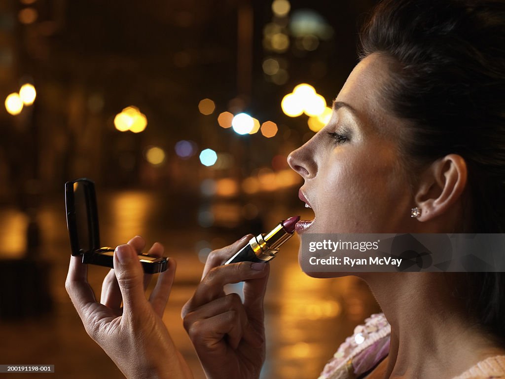 Woman applying lipstick, profile, close-up