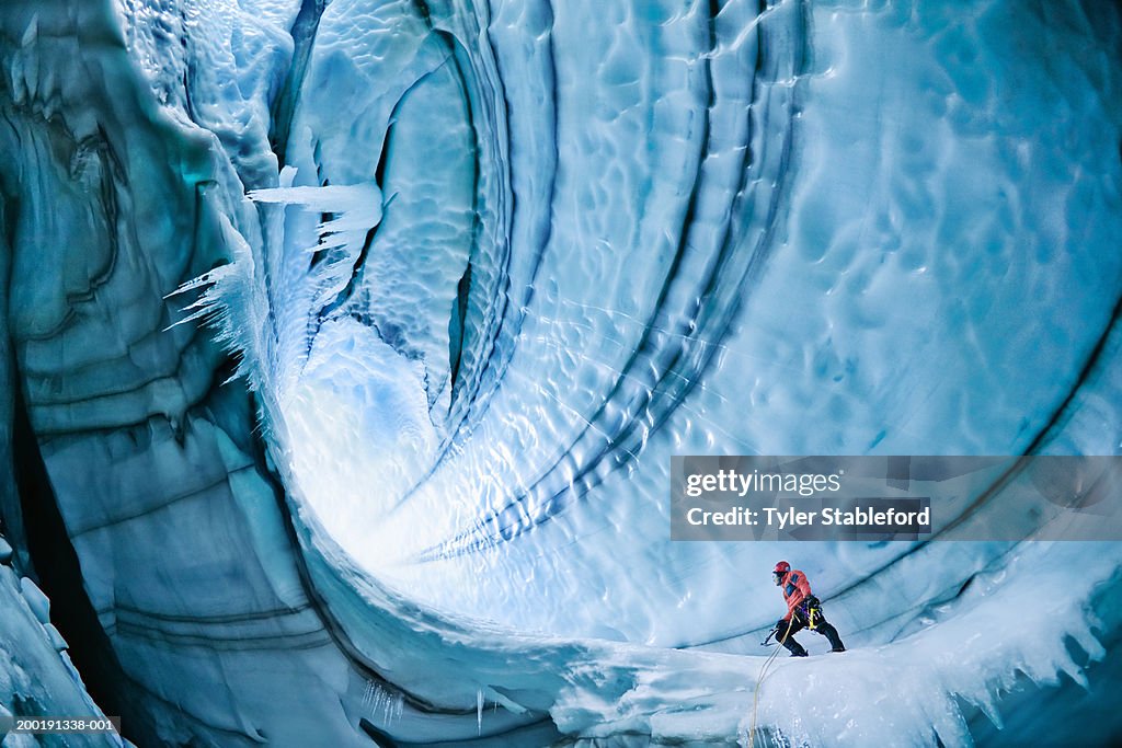 Male ice climber exploring ice cave, low angle view