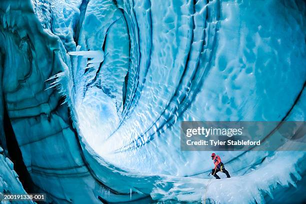 male ice climber exploring ice cave, low angle view - escalar no gelo imagens e fotografias de stock